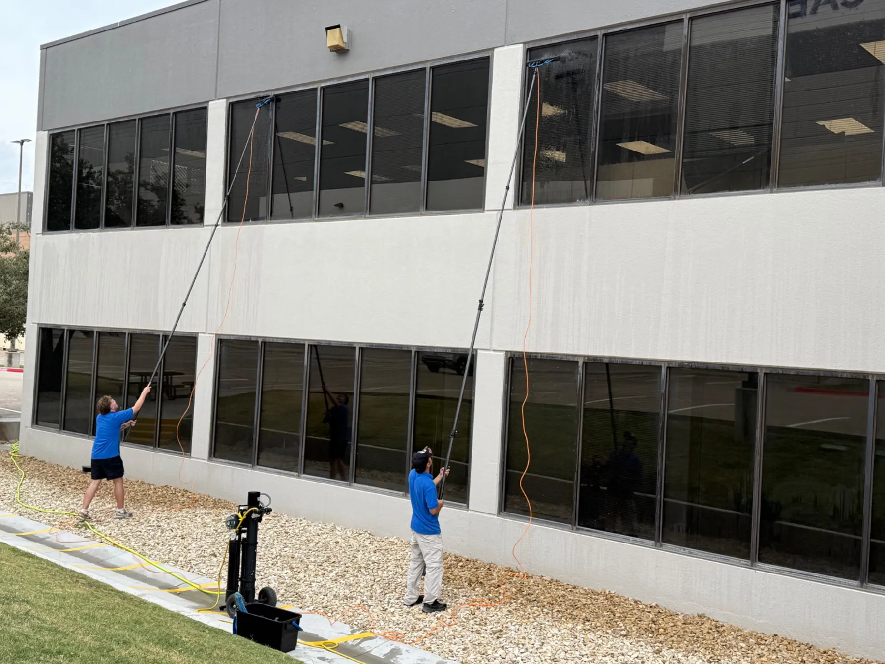 Brite-Way technician cleaning upper commercial windows using a Pure Water Cleaning system